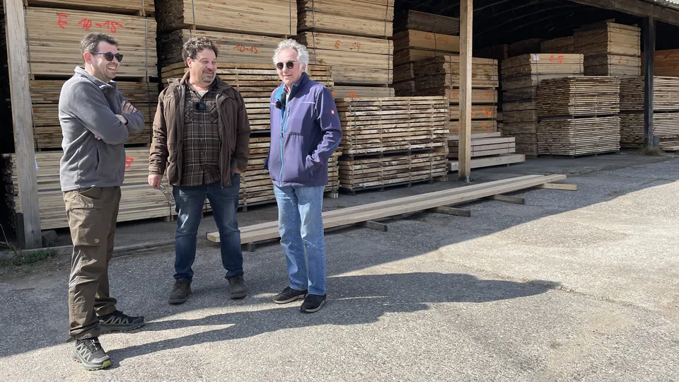 Markus Löhr mit Vater und Sohn Schmitz vor gestapelten Eichenbohlen am Sägewerk in Hamm an der Sieg