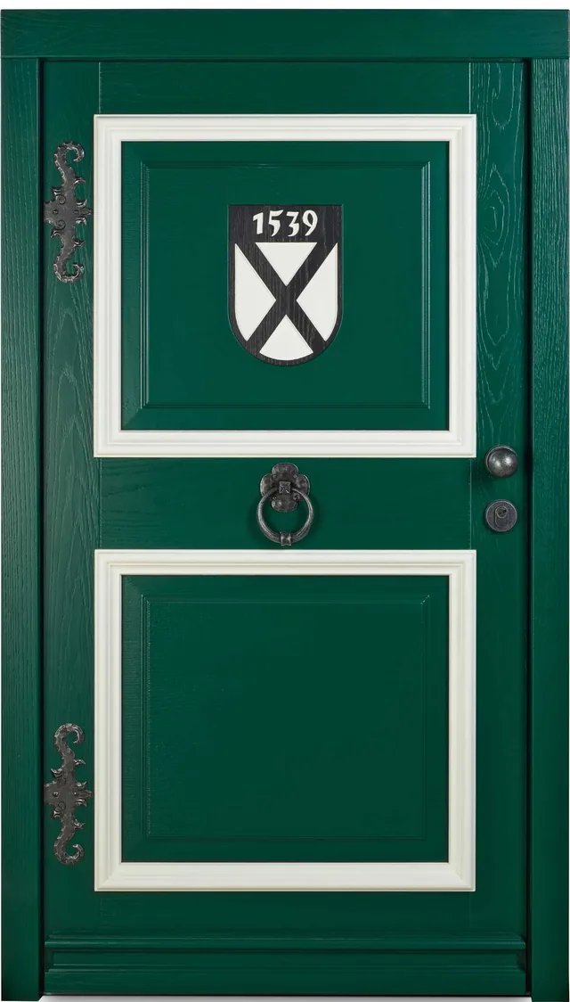 Grüne Haustür mit weiß abgesetzten Feldern, geschmiedeten Zierbändern und einem Wappenschild mit der Jahreszahl 1539